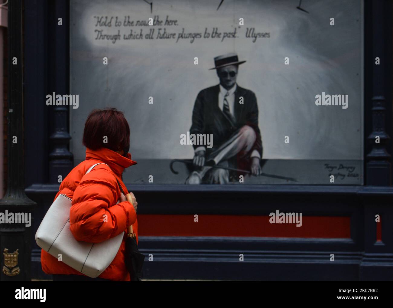 A woman walks by a closed pub in Dublin city center during Level 5
