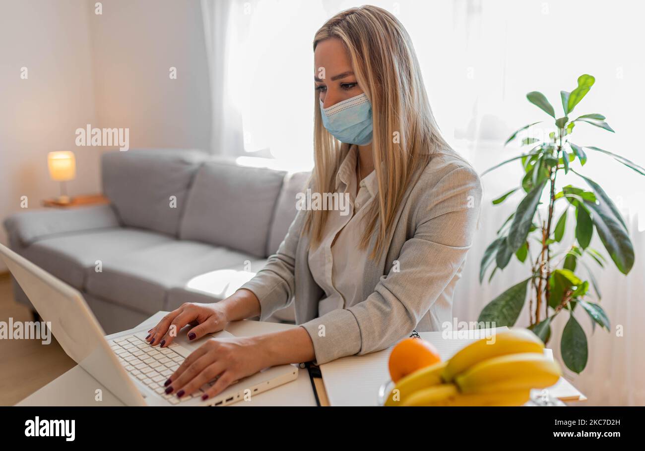 Female employee wearing medical face mask while working in the business office during covid-19 pandemic. Businesswoman wearing face mask Stock Photo