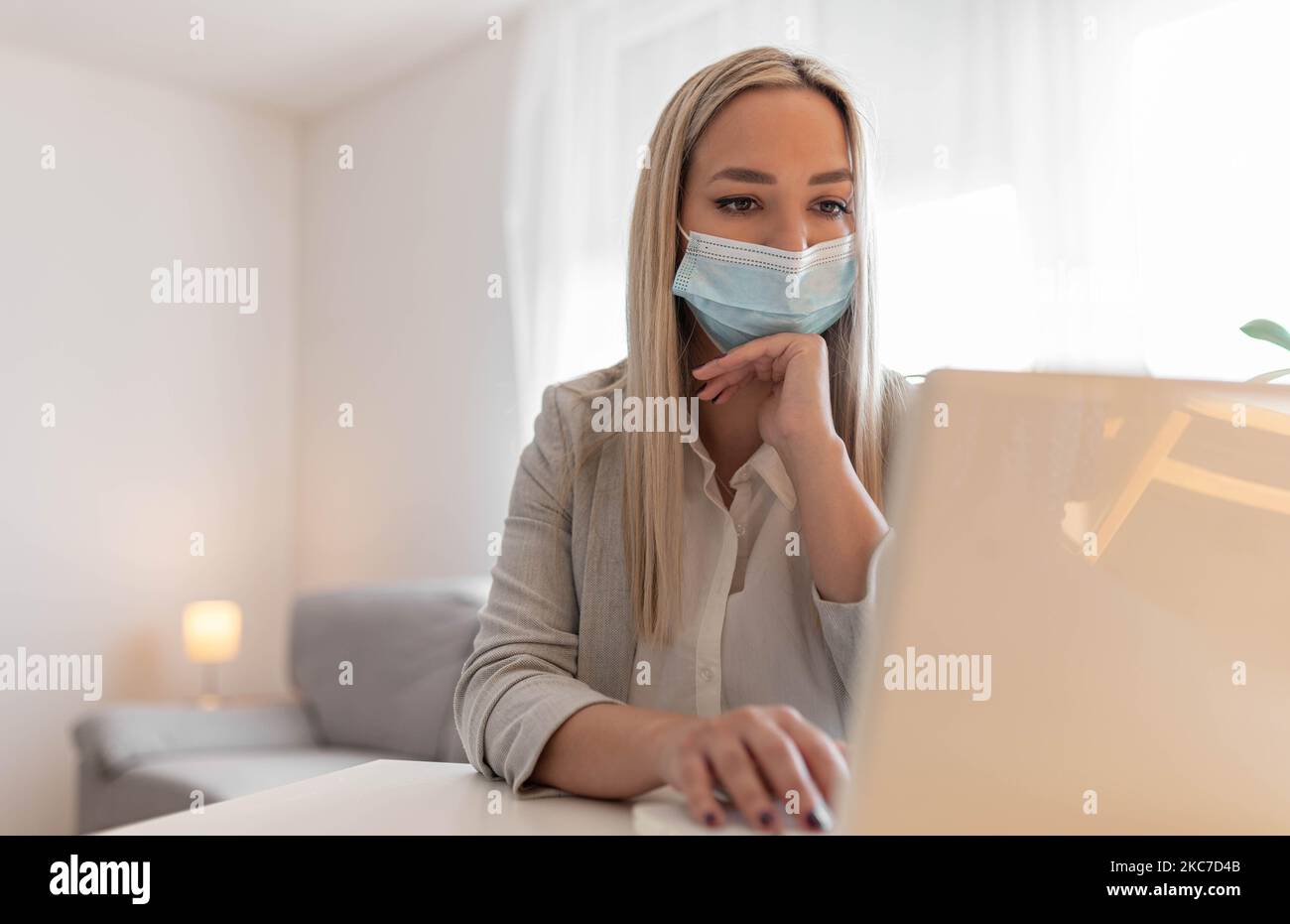 Female employee wearing medical face mask while working in the business office during covid-19 pandemic. Businesswoman wearing face mask Stock Photo