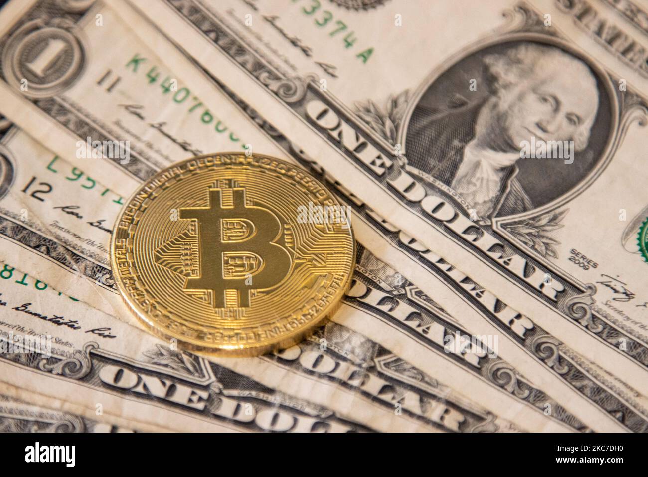 Bitcoin golden physical coin illustration on United States Dollar banknotes. Visual representations of the digital Cryptocurrency Bitcoin with the USD bill. Bitcoin with the symbol BTC, XBT is a popular digital currency that showed growth and is widely spread, accepted from banks, markets and other services and shops as ways of payments. The exchange rate today for 1 bitcoin blockchain is 34.588 US Dollar. On January 7, 2021 Bitcoin's price crossed 40,000 for the first time and the next day on January 8, 2021 Bitcoin traded with the historical record price as high as $41,973 while the next day Stock Photo