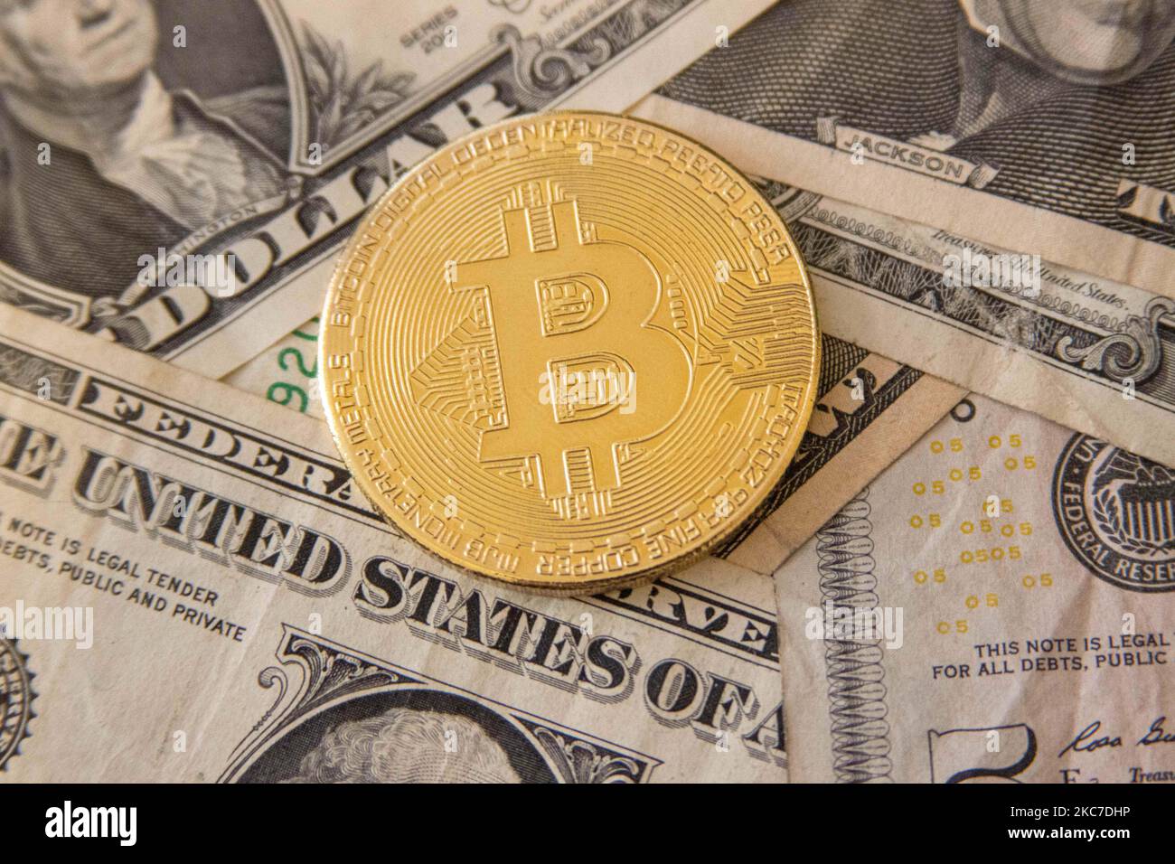 Bitcoin golden physical coin illustration on United States Dollar banknotes. Visual representations of the digital Cryptocurrency Bitcoin with the USD bill. Bitcoin with the symbol BTC, XBT is a popular digital currency that showed growth and is widely spread, accepted from banks, markets and other services and shops as ways of payments. The exchange rate today for 1 bitcoin blockchain is 34.588 US Dollar. On January 7, 2021 Bitcoin's price crossed 40,000 for the first time and the next day on January 8, 2021 Bitcoin traded with the historical record price as high as $41,973 while the next day Stock Photo