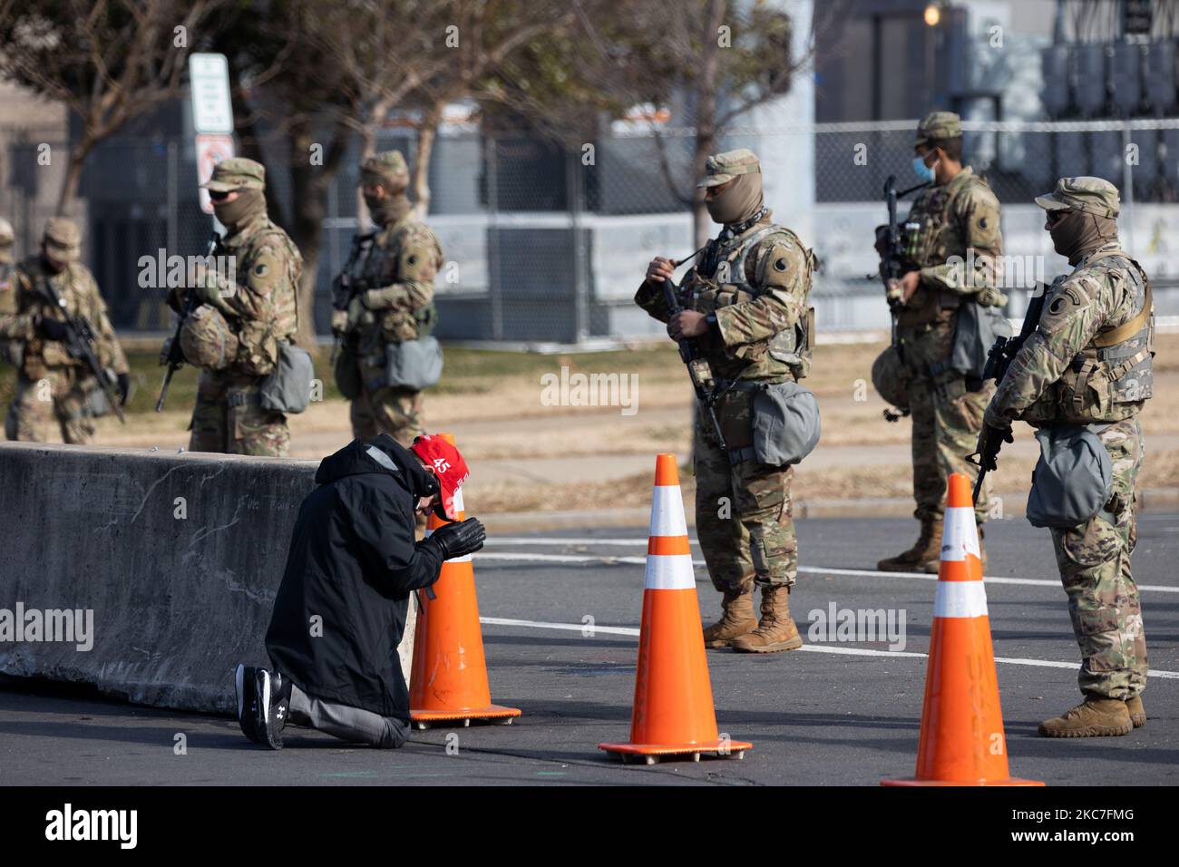 A President Donald Trump supporter wearing a MAGA hat is seen praying in front o Members of The National Guard outside The US Congress. Washington, D.C. January 14, 2021. (Photo by Aurora Samperio/NurPhoto) Stock Photo