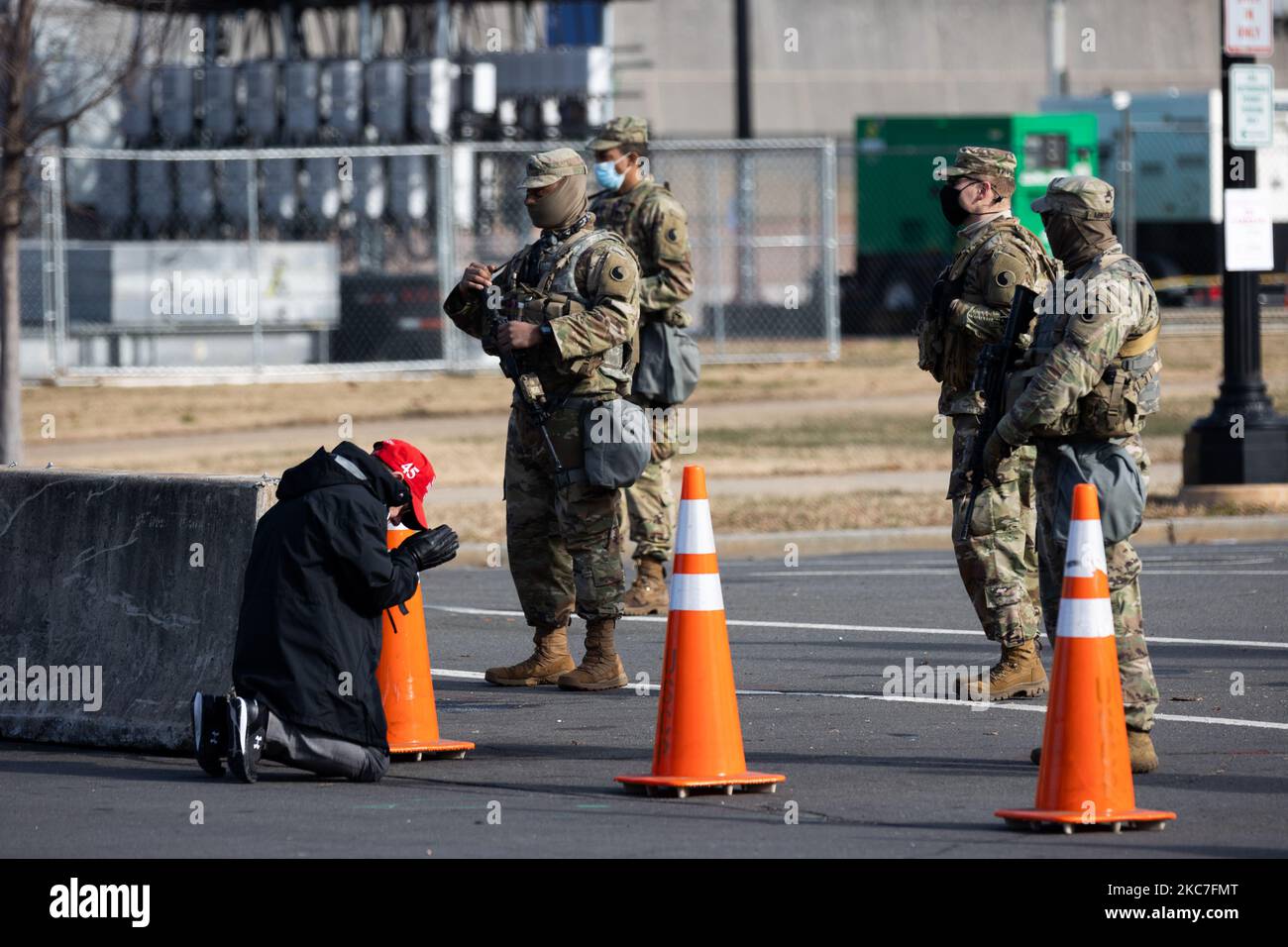 A President Donald Trump supporter wearing a MAGA hat is seen praying in front o Members of The National Guard outside The US Congress. Washington, D.C. January 14, 2021. (Photo by Aurora Samperio/NurPhoto) Stock Photo