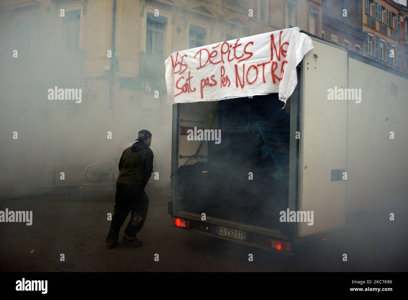 A man runs amid clouds of tear gas. The banner reads 'You offences aren't ours'. Thousands of protesters marched again against the 'Global Security Law' bill promoted by French President Macron and his majority. Culture people and ravers joined the demonstration as a rave party organizers risk up to 10 years in jail for organizing a freeparty during New Eve. Culture people protest as theaters, cinemas, concerts hall are closed since months. The 'Global Security Law' bill will forbid anyone to photograph or film police members if not flouted : transgressors could be condemned up to one year in  Stock Photo