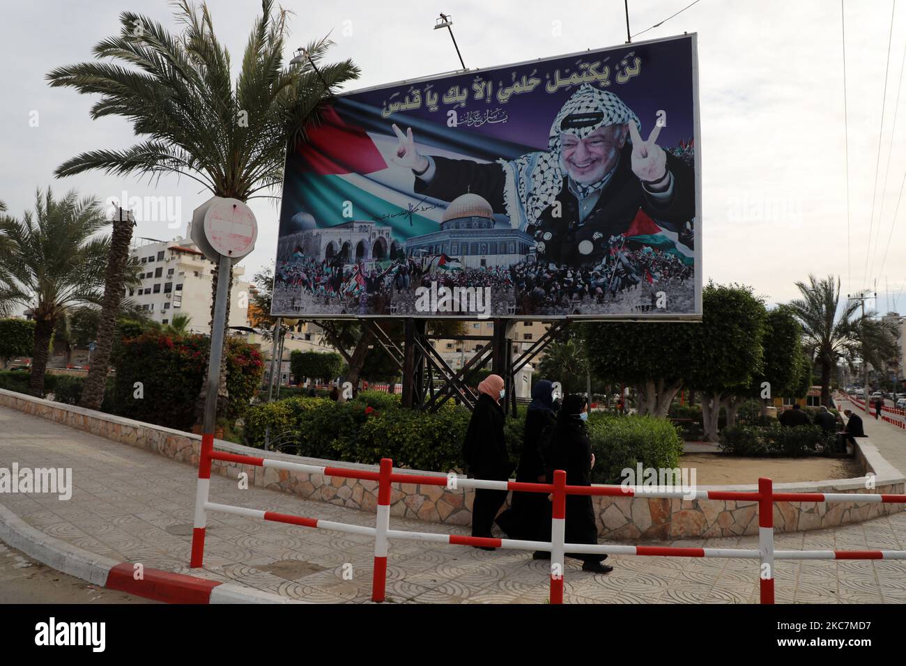 Palestinians women walk past a mural depicting late leader Yasser Arafat in Gaza City, on January 17, 2021 - Palestinian president Mahmud Abbas announced dates for the first Palestinian elections in more than 15 years, setting legislative polls for May 22 and a July 31 presidential vote. Abbas's Fatah party, which controls the Palestinian Authority based in the occupied West Bank, and the Hamas Islamists, who hold power in Gaza, have for years expressed interest in taking Palestinians back to the polls. (Photo by Majdi Fathi/NurPhoto) Stock Photo