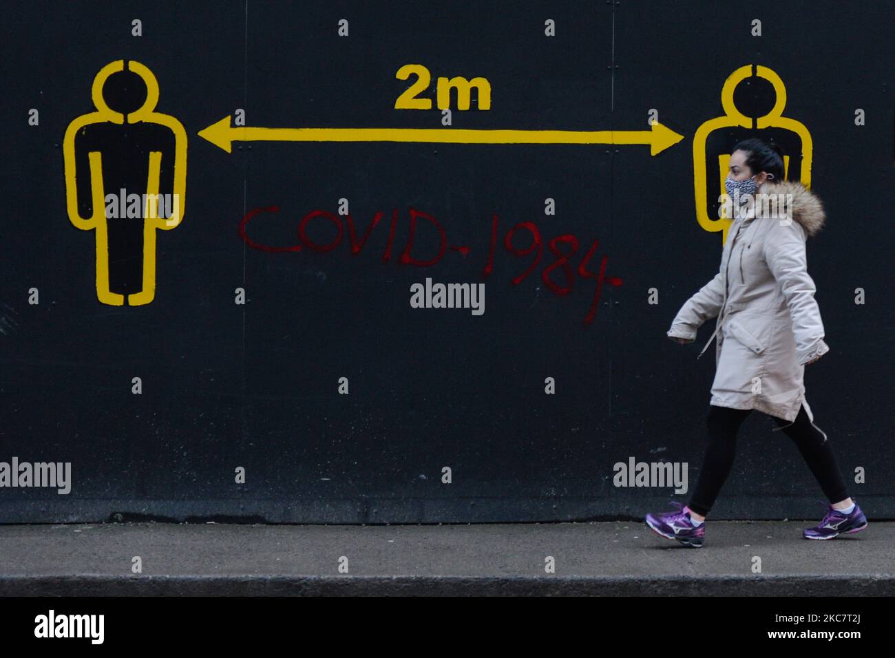 A woman walks by a sign 2metres in Dublin city centre during Level 5 Covid-19 lockdown. The Department of Health reported this evening 2,001 of new Covid-19 cases for the Republic of Ireland and 93 deaths, a new record for a confirmed number of daily deaths. On Tuesday, 19 January, 2021, in Dublin, Ireland. (Photo by Artur Widak/NurPhoto) Stock Photo