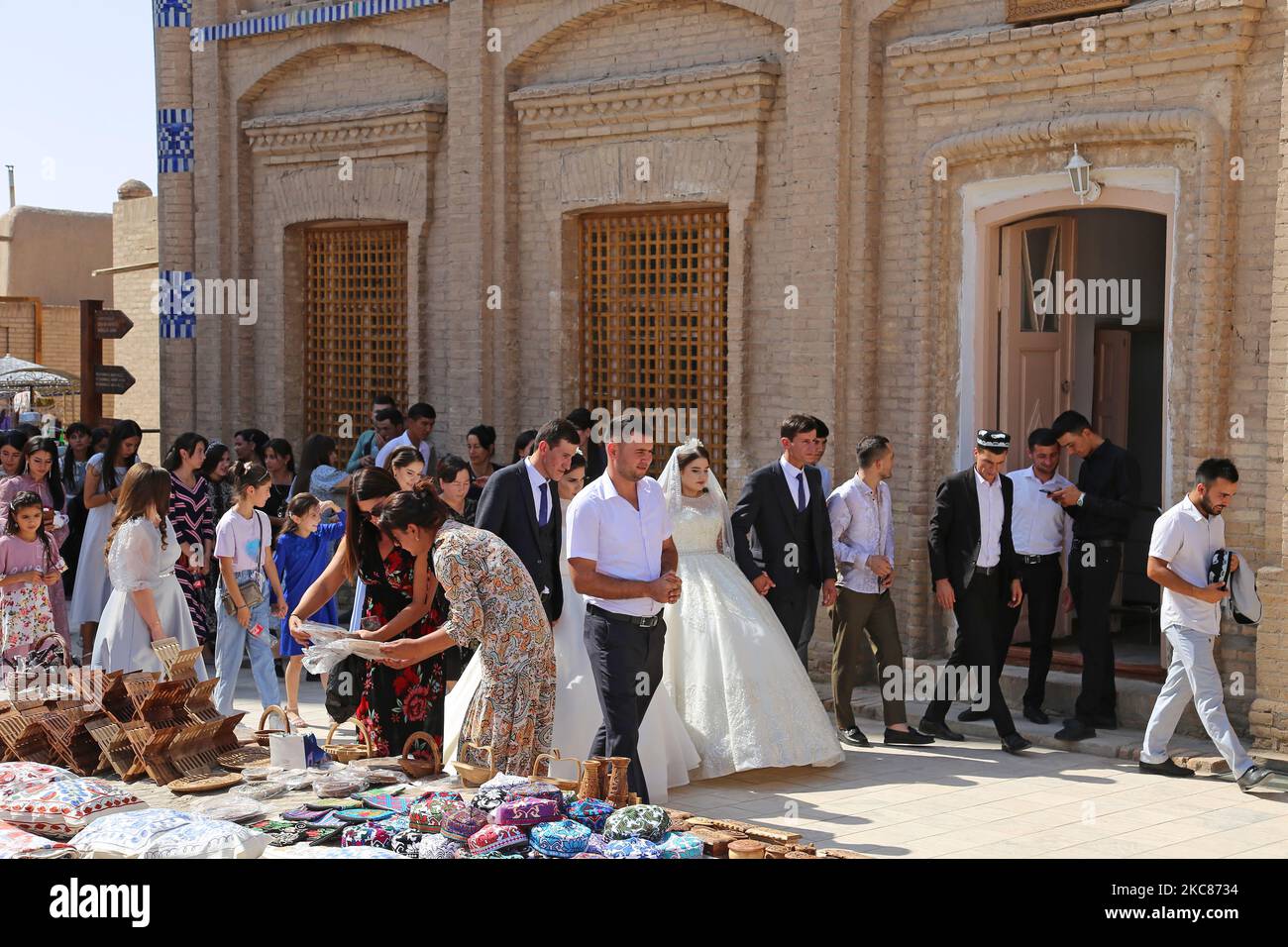 Two wedding parties pass the New Method School, Islam Khoja Street, Ichan Kala (Inner Fortress), Khiva, Khorezm Province, Uzbekistan, Central Asia Stock Photo