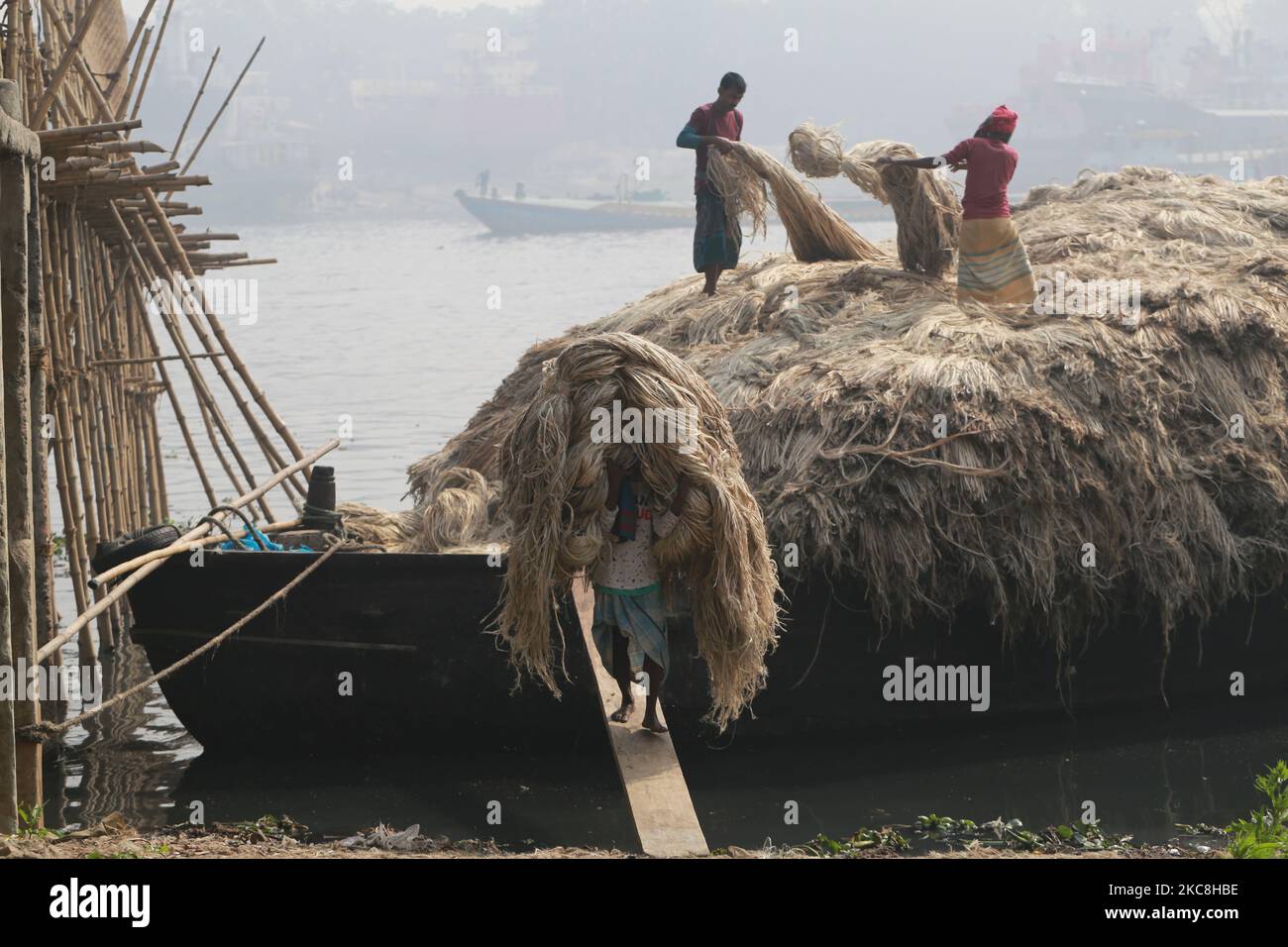 Labors unload jute from a boat for processing to be exported on the