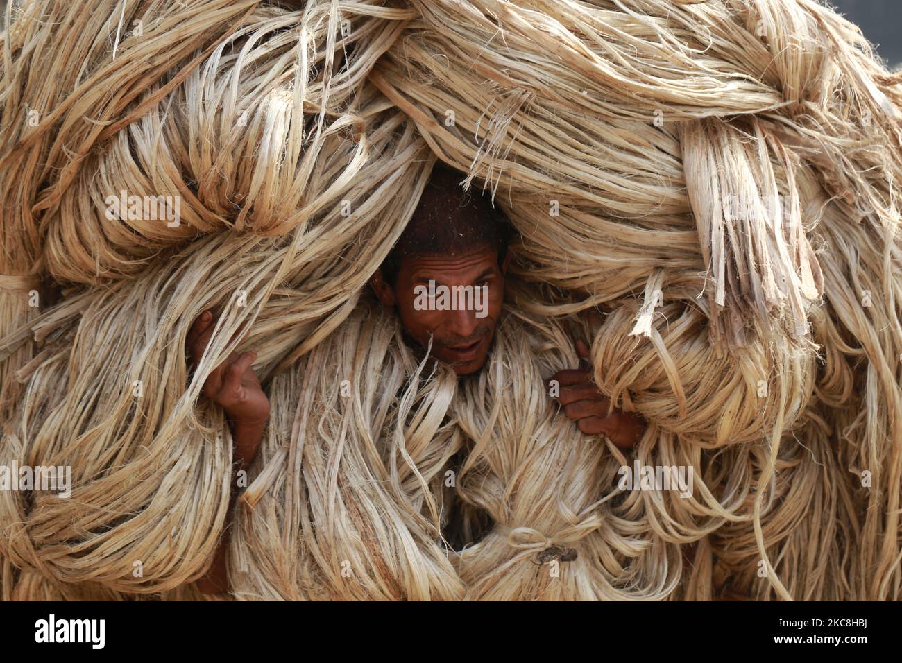 A labor carries jute for processing to be exported at a factory in