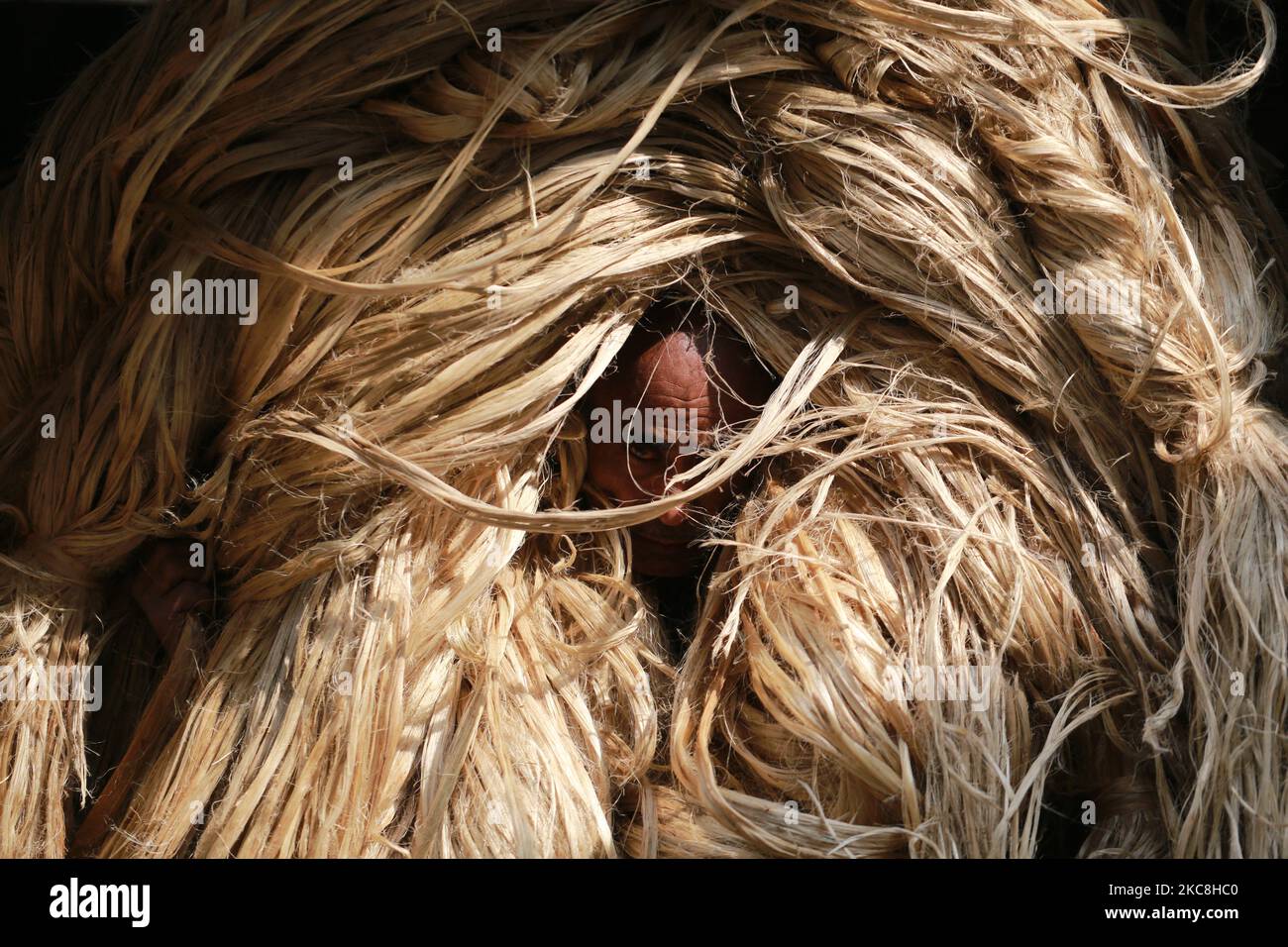 A labor carries jute for processing to be exported at a factory in