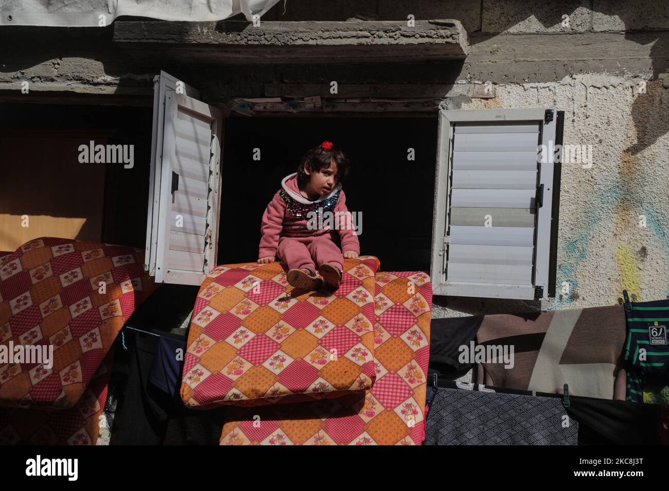 A Palestinian girl looks out the window of her family's house at Deir ...
