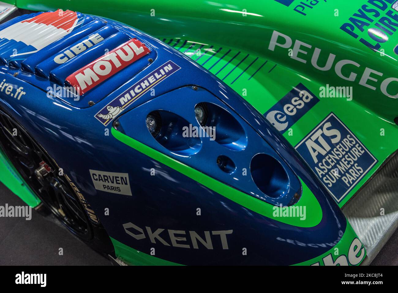 A closeup of a blue and green Peugeot racecar headlight standing on the