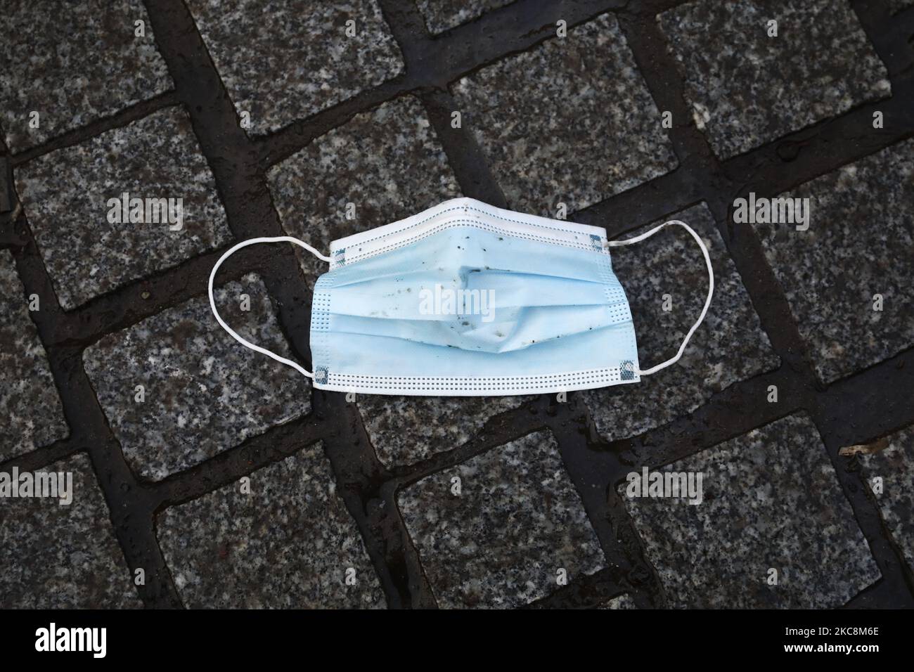 A disposable face mask is seen lying on a pavemment during coronavirus pandemic in Gliwice, Poland on February 3, 2021. (Photo by Beata Zawrzel/NurPhoto) Stock Photo