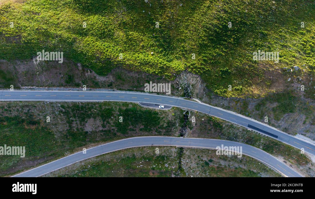 An aerial view of zigzag road built on a mountain, past the forest
