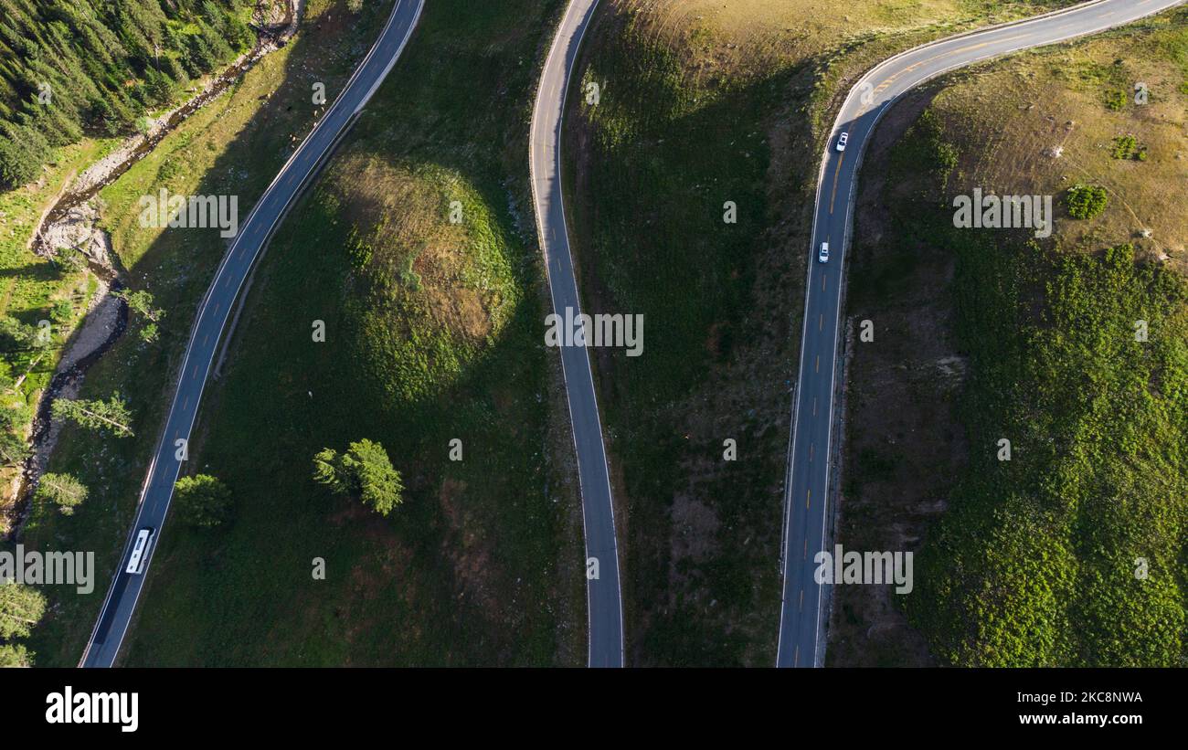 An aerial view of zigzag road built on a mountain, past the forest