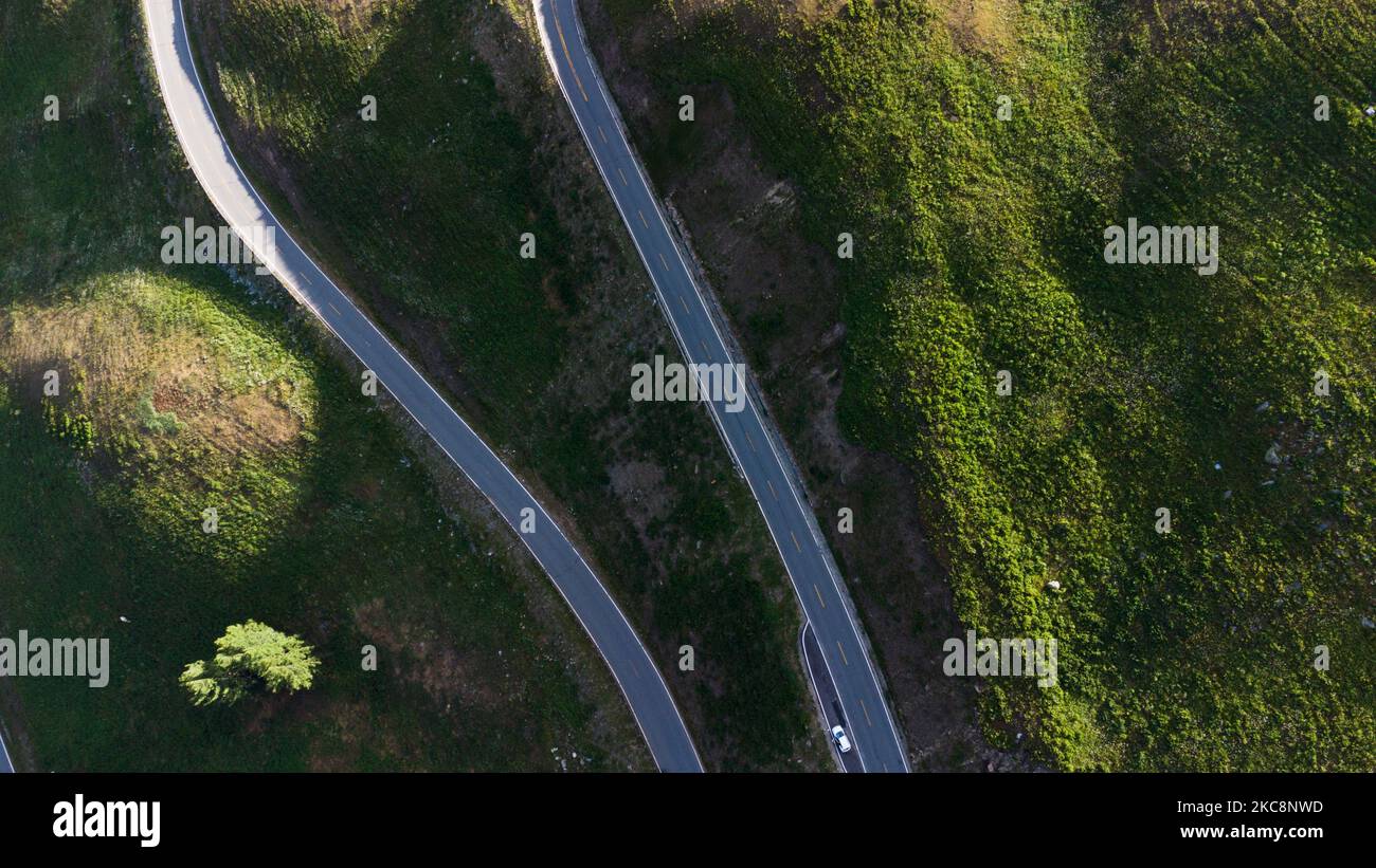 An aerial view of zigzag road built on a mountain, past the forest
