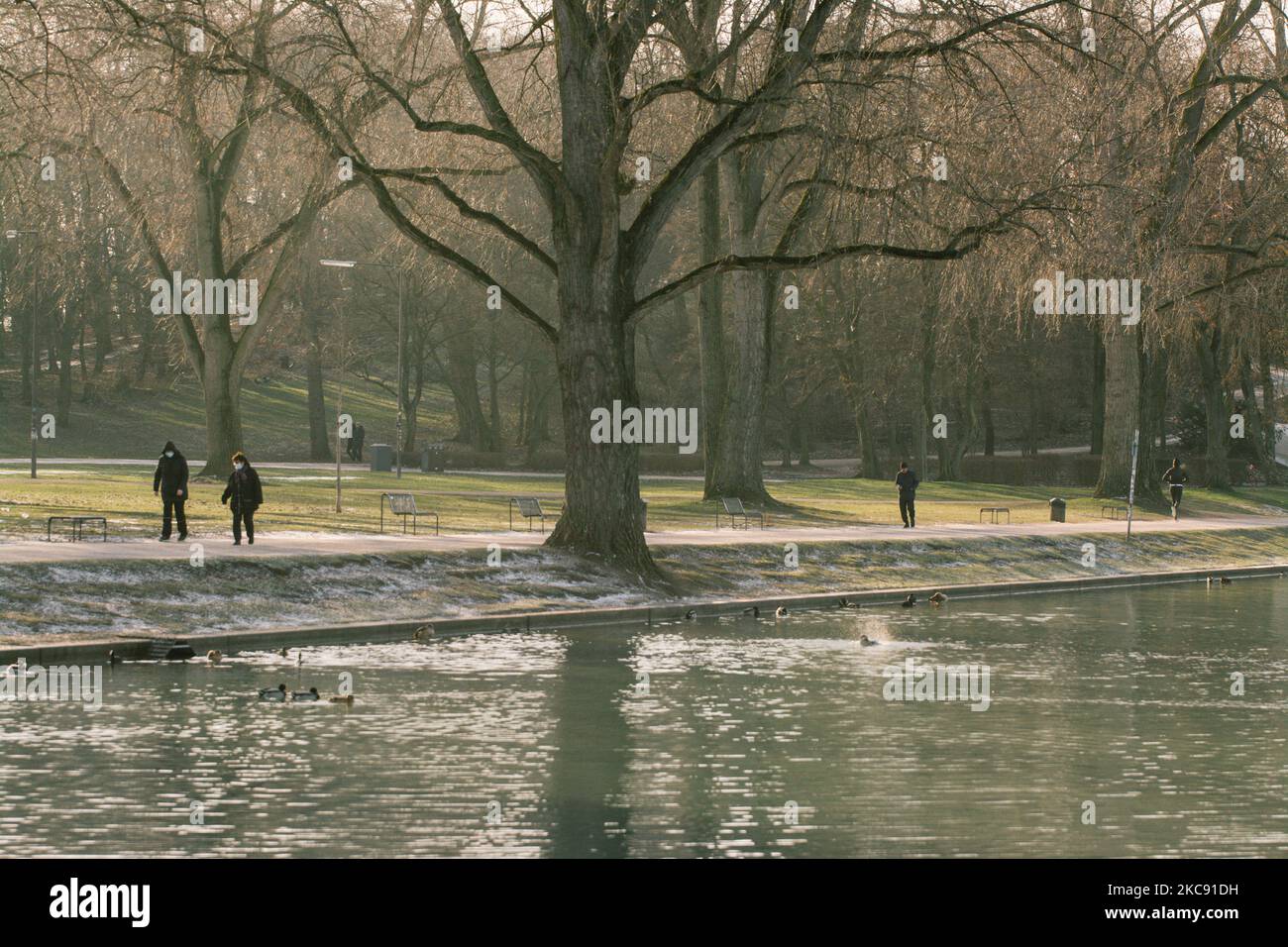 people walk in the Hiroshima Nagasaki park in Cologne as the chilly temperatures will continues