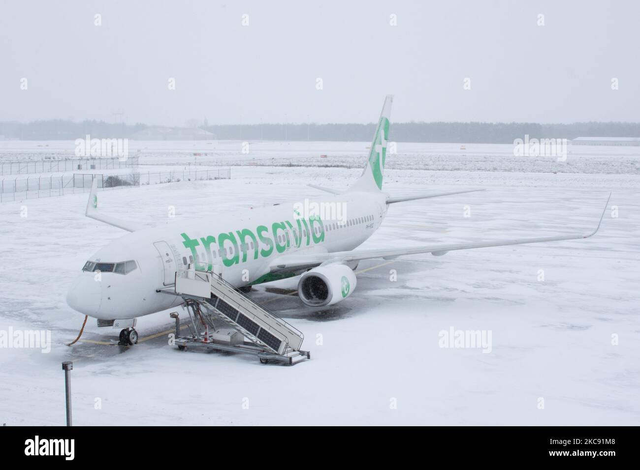 Grounded Transavia fleet, Boeing 737 in Eindhoven airport due to the snow. Snowstorm shuts down the airport of Eindhoven EIN in the Netherlands. Heavy snow fall disrupts the air traffic that caused diversions to Germany on Sunday. Blizzard from storm Darcy hit the country since Sunday morning (07.02.2021) resulting problems in public transportation. In the snow-covered Eindhoven airport, Transavia airplanes are seen grounded while heavy machinery is cleaning the taxiway and runway. Dozens of flights that were due to depart were delayed or canceled at Schiphol Airport in Amsterdam due to the ar Stock Photo