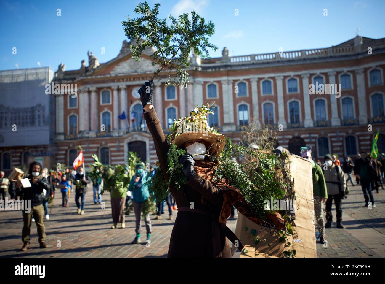 A woman gestures with branchs in front of the townhall of toulouse. Several associations, political parties and people united in a collective 'Touche pas a ma foret' (ie 'Don't touch my forest') called for a die-in in Toulouse in front of the townhall, the Capitole, to symbolize their opposition to a global firm, Florian. The sawmill company Florian wants to build a giant sawmill near the Pyrenean town of Lannemezan. The sawmill is expected to treat nearly 400.000 cubic meters of beech wood each year. For this, the Florian company will need to cut beech trees all over the French Pyrenees. It i Stock Photo