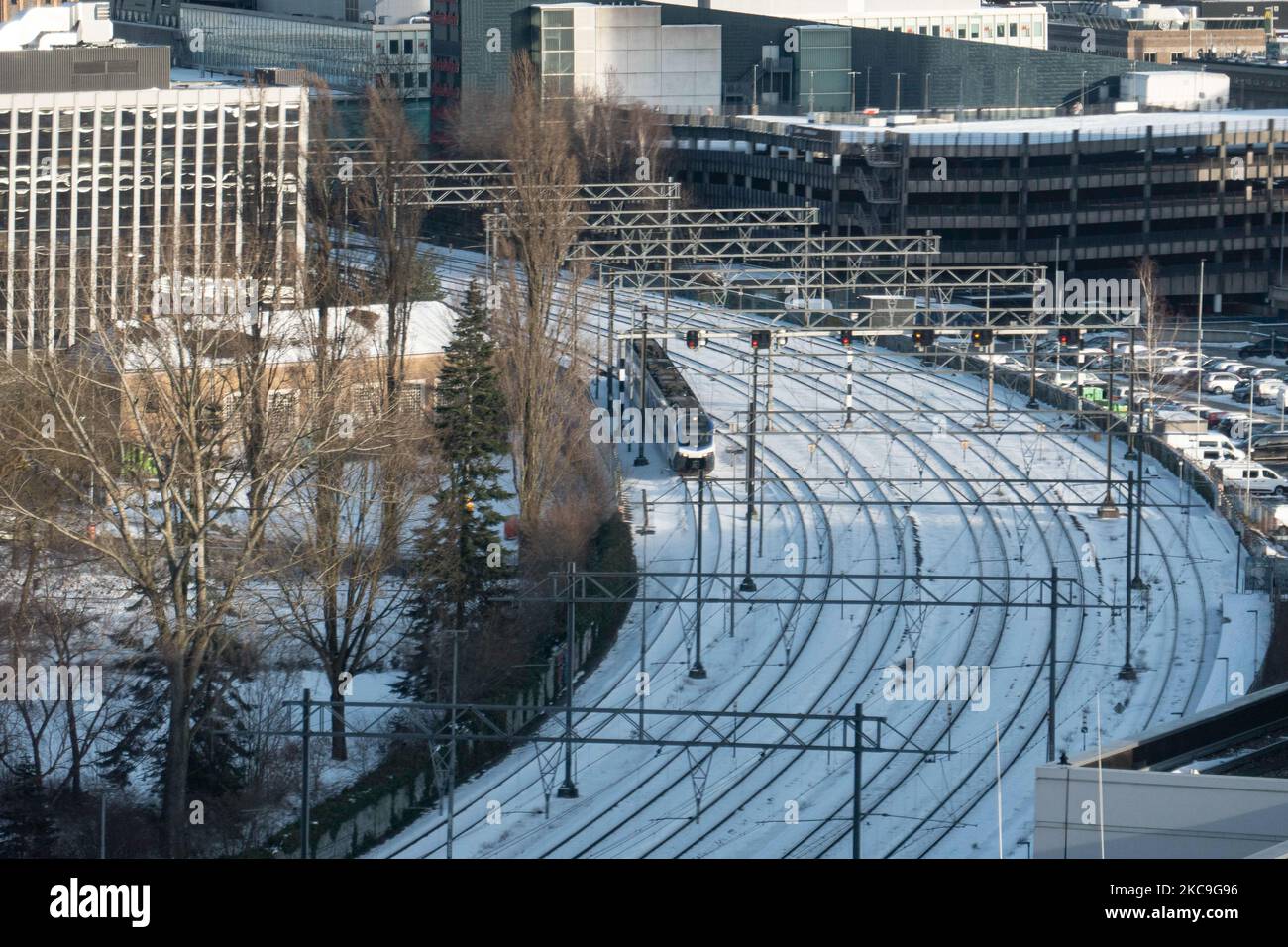 A train on the snow covered tracks in the city center. Panoramic overview of the snow covered Dutch city of Eindhoven as seen in the center and residential areas, while the snow covered the roads, railway, roofs for a period of over a week resulting also lakes and canals to freeze. Eindhoven, The Netherlands on February 2021 (Photo by Nicolas Economou/NurPhoto) Stock Photo