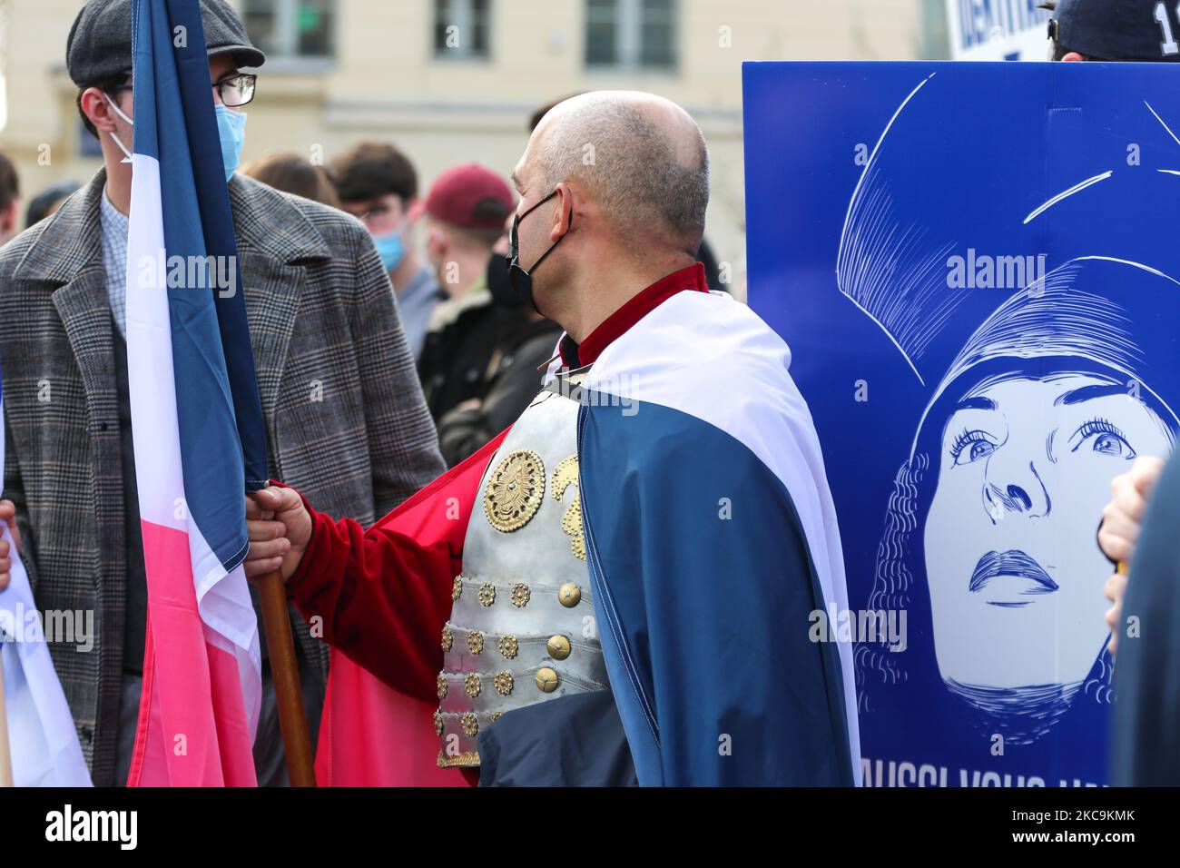 Member of far right group Generation Identitaire (GI) holds the French flag in front of the portrait of Joan d’Arc during a protest against its potential dissolution in Place Denfert Rochereau, in Paris on February 20, 2021. The dissolution of Generation identitaire was evoked for the first time on January 26, 2021 by Interior Minister, as a reaction to the group's recent anti-migrant operation in the Pyrenees, which led to a preliminary investigation for provocation to racial hatred. (Photo by Michel Stoupak/NurPhoto) Stock Photo