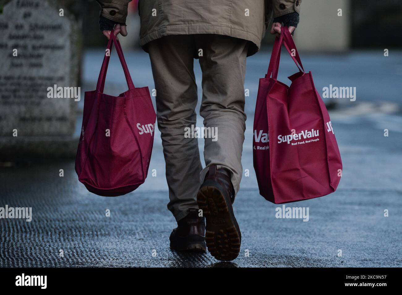 A man carries two SuperValu shopping bags in Dun Laoghaire during Level 5 Covid-19 lockdown. On Saturday, February 20, 2021, in Dún Laoghaire, Dublin, Ireland. (Photo by Artur Widak/NurPhoto) Stock Photo