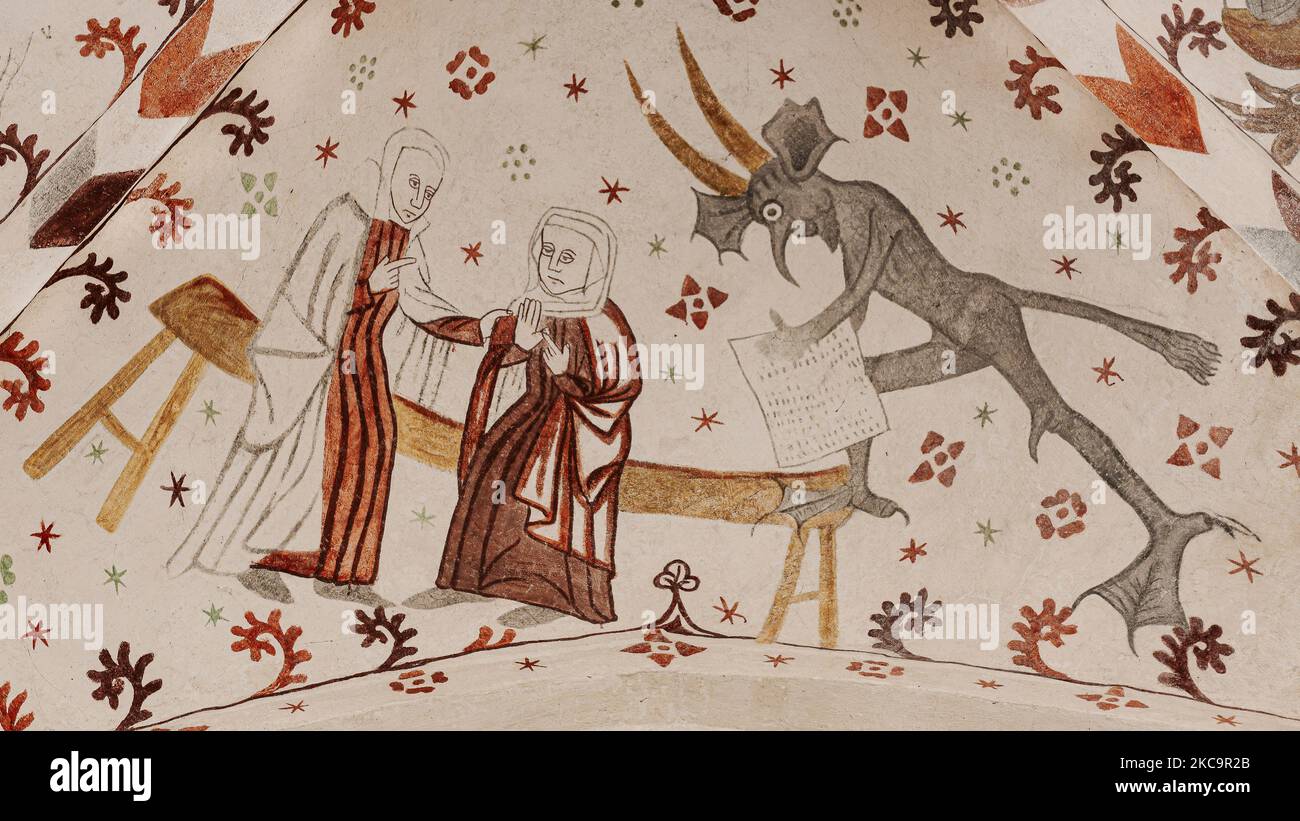 Medieval fresco with two women gossiping and a devil takes notes in Fanefjord church, Denmark, October 10, 2022 Stock Photo