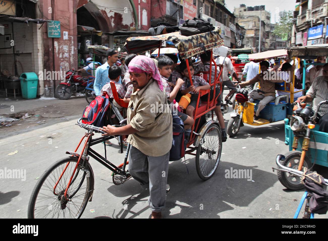 School children travel in an overload rickshaw along a busy street in ...