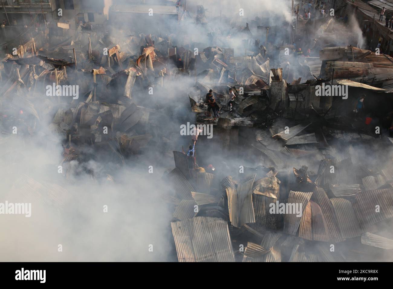 Firefighters, volunteers extinguish a fire at a slum in Dhaka ...