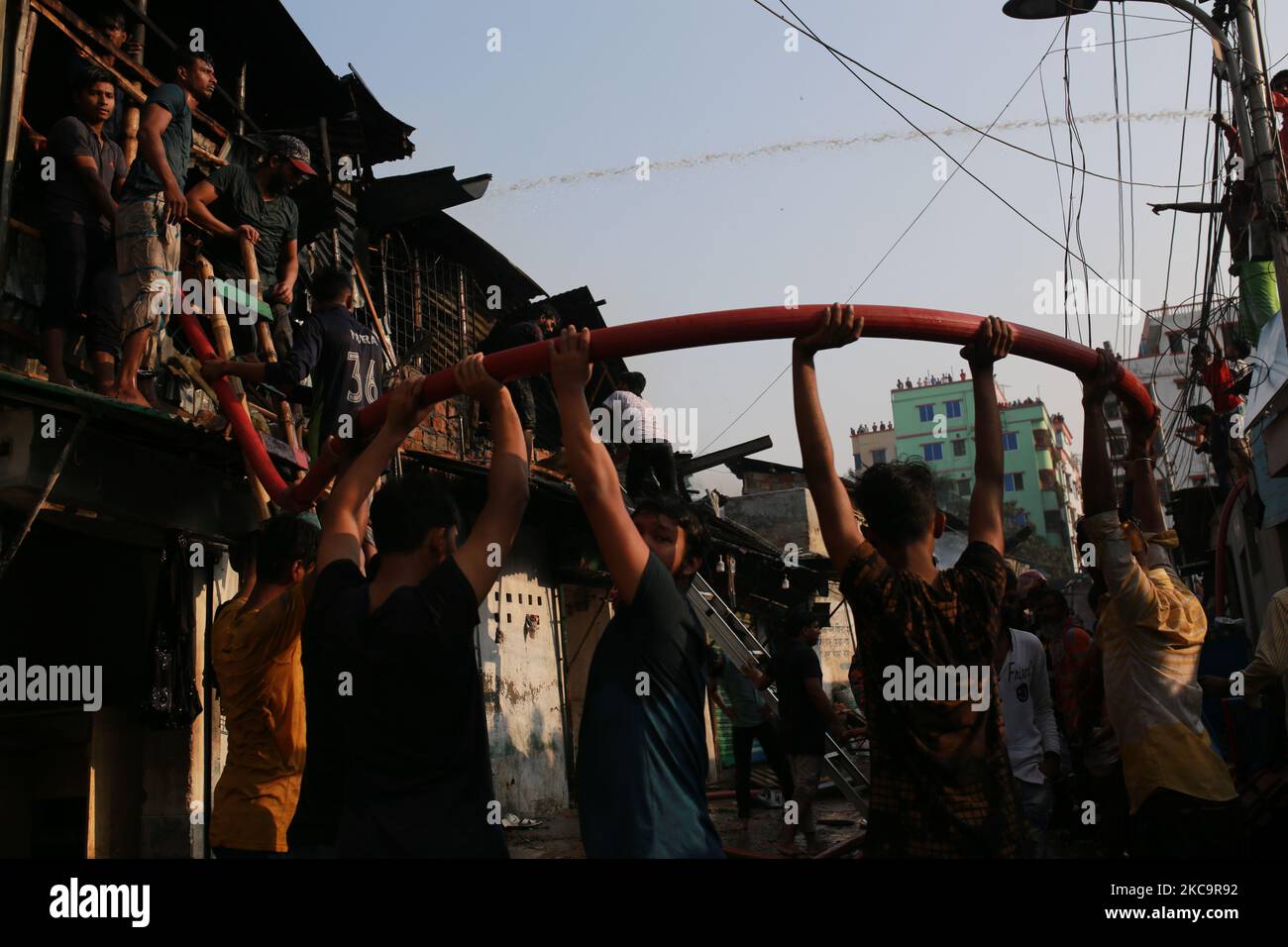Firefighters, volunteers extinguish a fire at a slum in Dhaka ...
