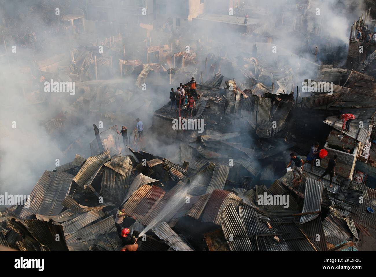 Firefighters, volunteers extinguish a fire at a slum in Dhaka ...
