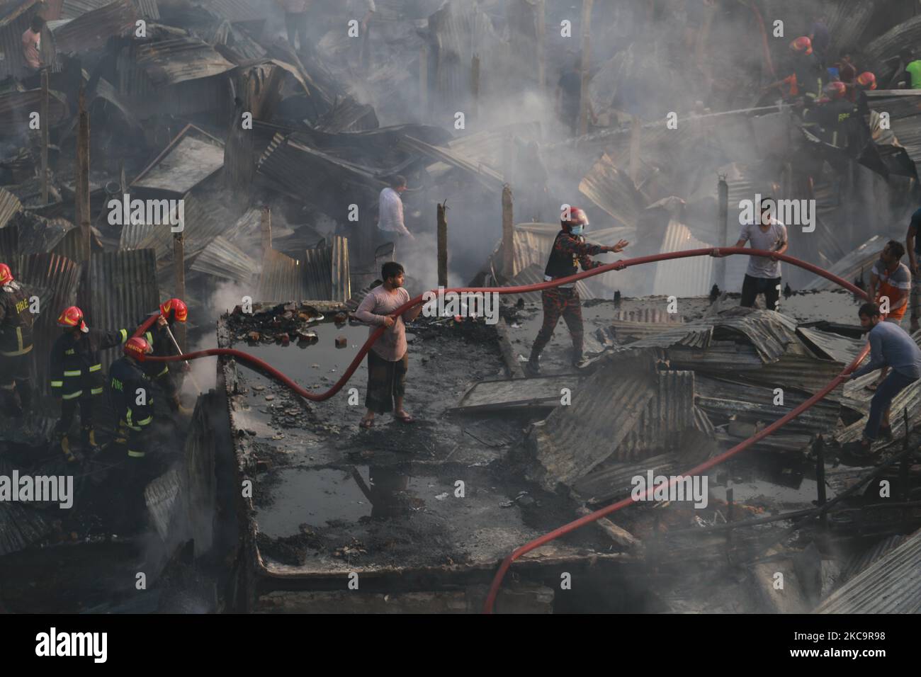 Firefighters, volunteers extinguish a fire at a slum in Dhaka ...