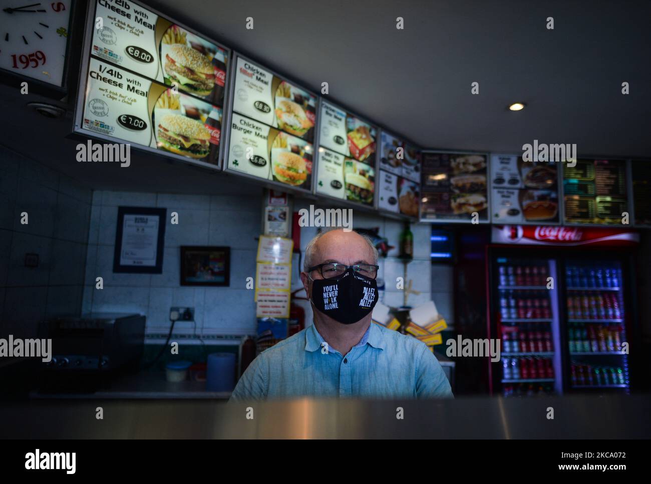 A man wearing a face mask with an inscription 'You'll never walk alone' inside a traditional chipper takeaway in Dublin 8 area, during Level 5 Covid-19 lockdown. On Thursday, February 25, 2021, in Dublin, Ireland. (Photo by Artur Widak/NurPhoto) Stock Photo
