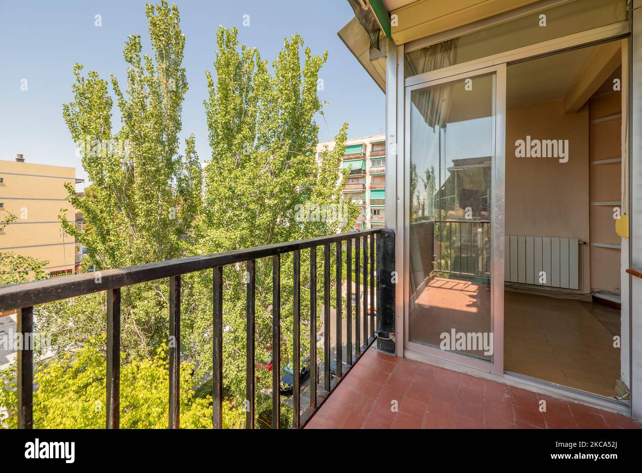 terrace of a house with clay floors, metal railing and sliding aluminum