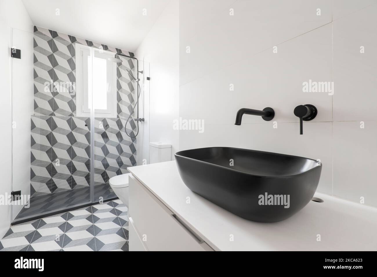Minimalist design bathroom with wall cabinet, glass-enclosed cabin, black taps and black porcelain sink Stock Photo