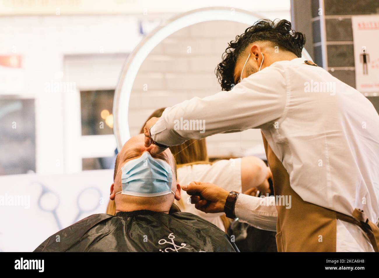 hairdressers cut the hair of a client in Salon Anis in Cologne, Germany