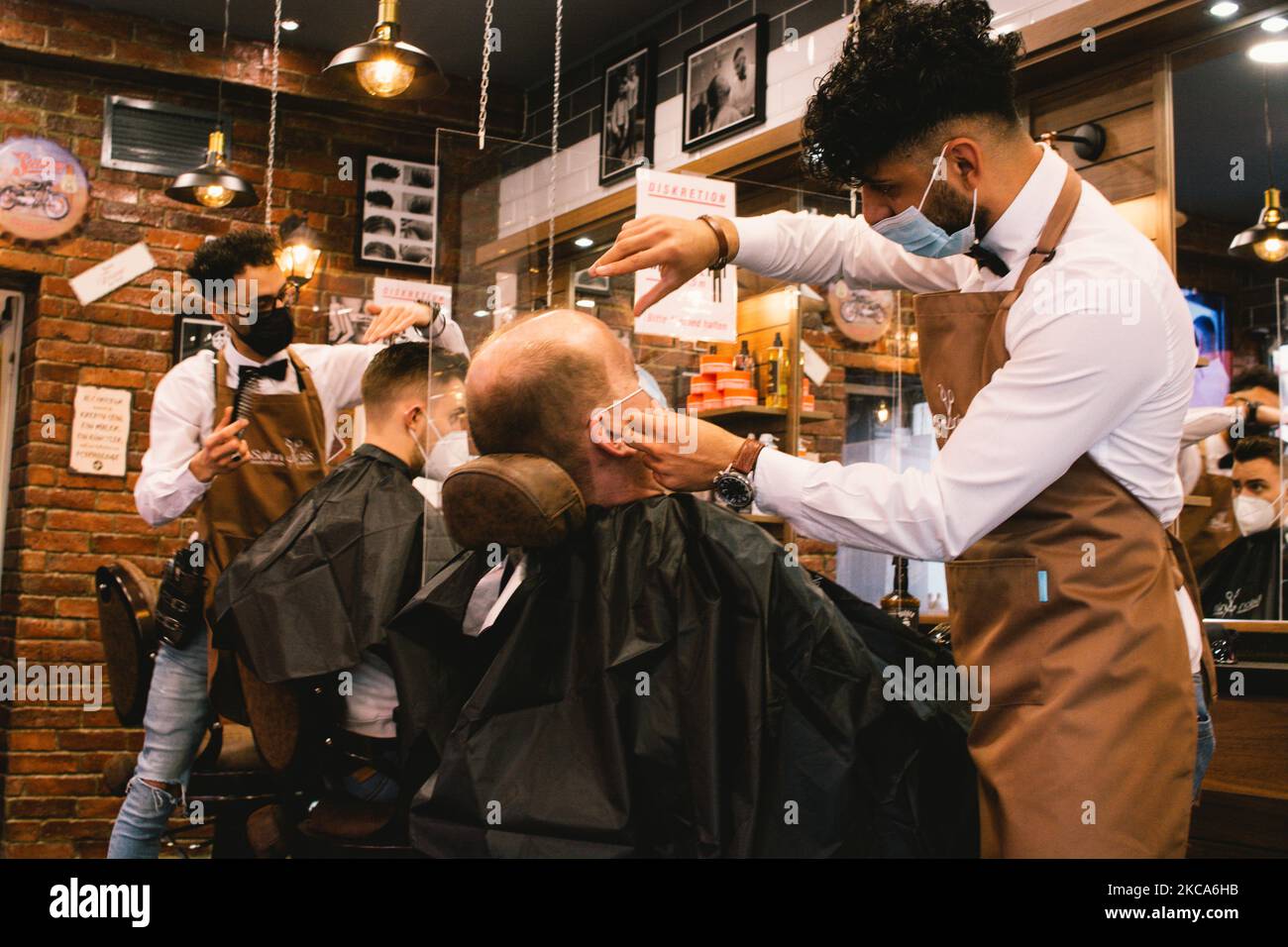 hairdressers cut the hair of a client in Salon Anis in Cologne, Germany
