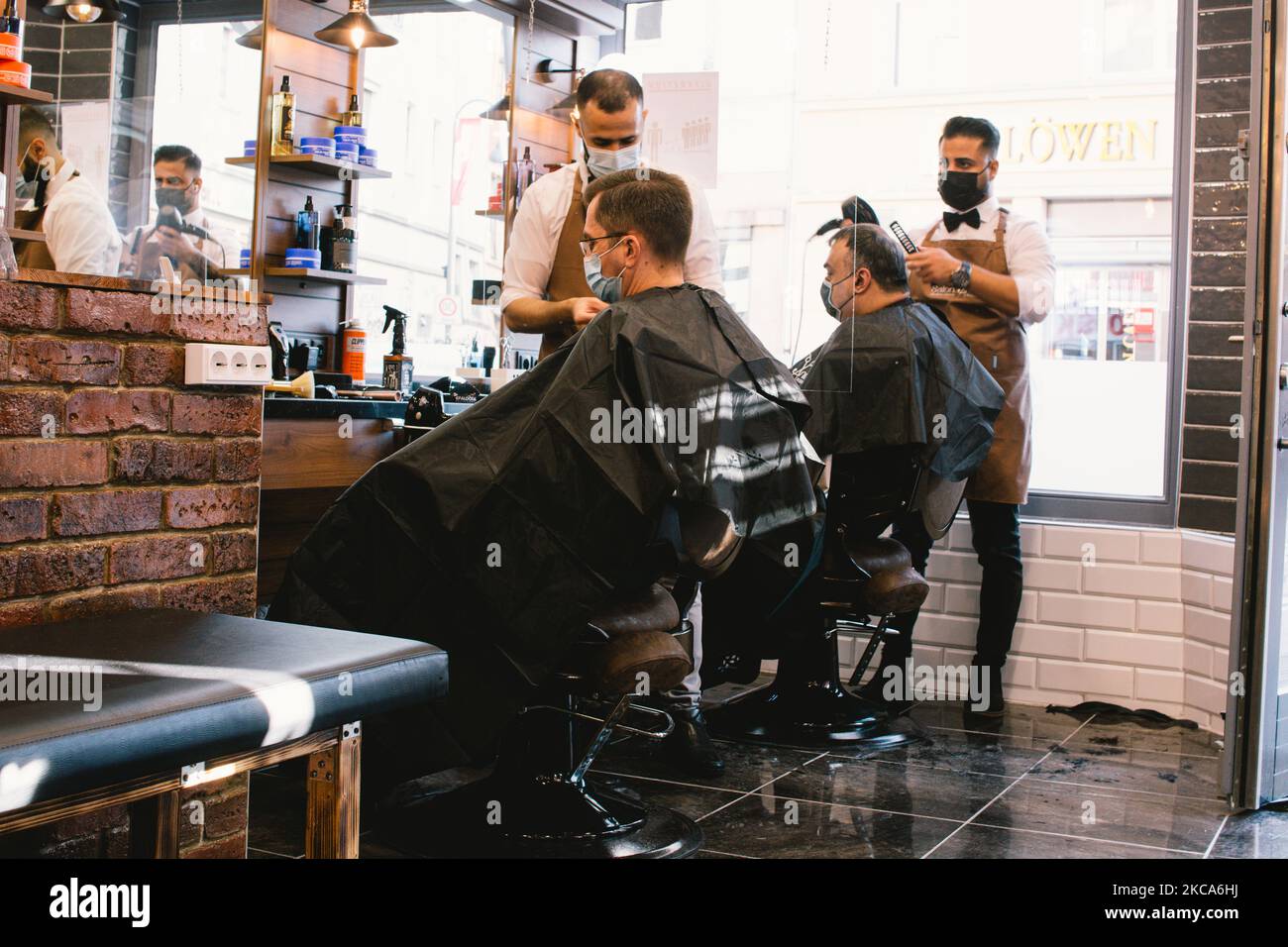 hairdressers cut the hair of a client in Salon Anis in Cologne, Germany