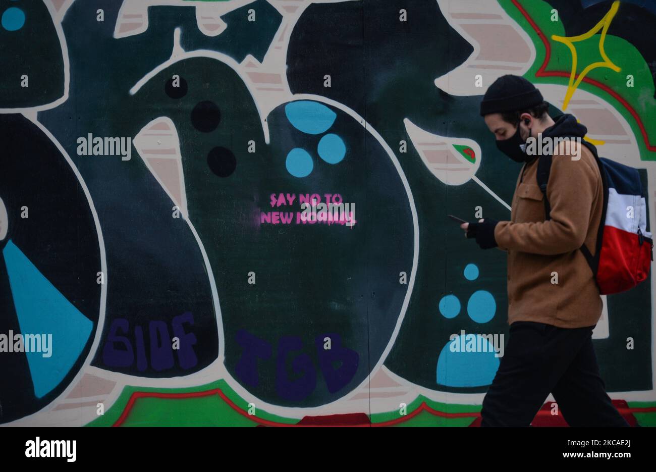 A man wearing a face mask passes in front of a mural with the inscription 'Say No To New Normal' seen in Dublin city center during Level 5 Covid-19 lockdown. On Saturday, 6 March, 2021, in Dublin, Ireland. (Photo by Artur Widak/NurPhoto) Stock Photo