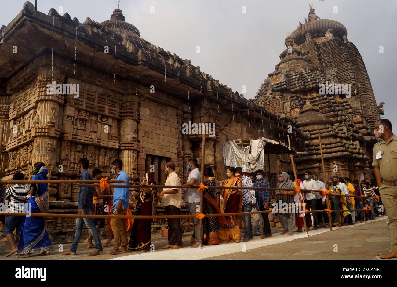 Devotees stand in the queue as they wait for their turn to offer puja ...