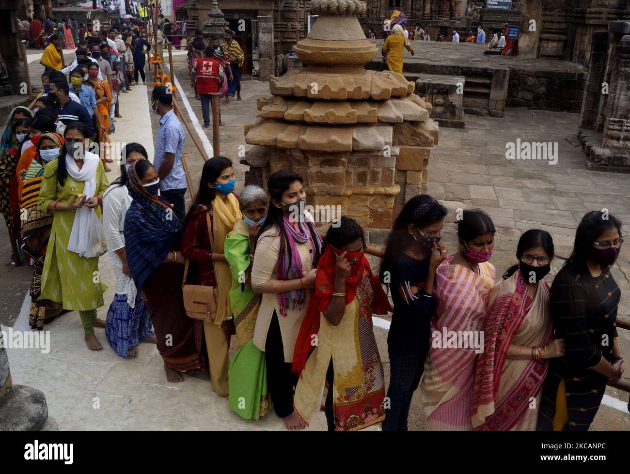 Devotees stand in the queue as they wait for their turn to offer puja ...