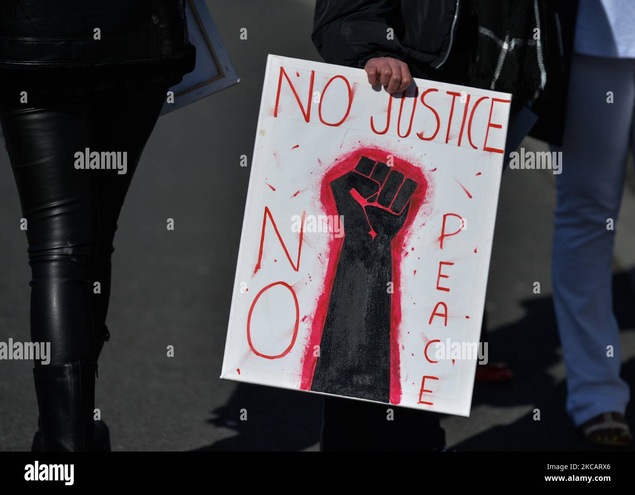 A person holds a poster that reads 'No Justice No Peace' outside the grounds of Sacred Heart of Jesus Church in Huntstown, Dublin, at the funeral of George Nkencho who was shot outside his home by members of the Garda Armed Support Unit last December. On Saturday, March 13, 2021, in Dublin, Ireland. (Photo by Artur Widak/NurPhoto) Stock Photo