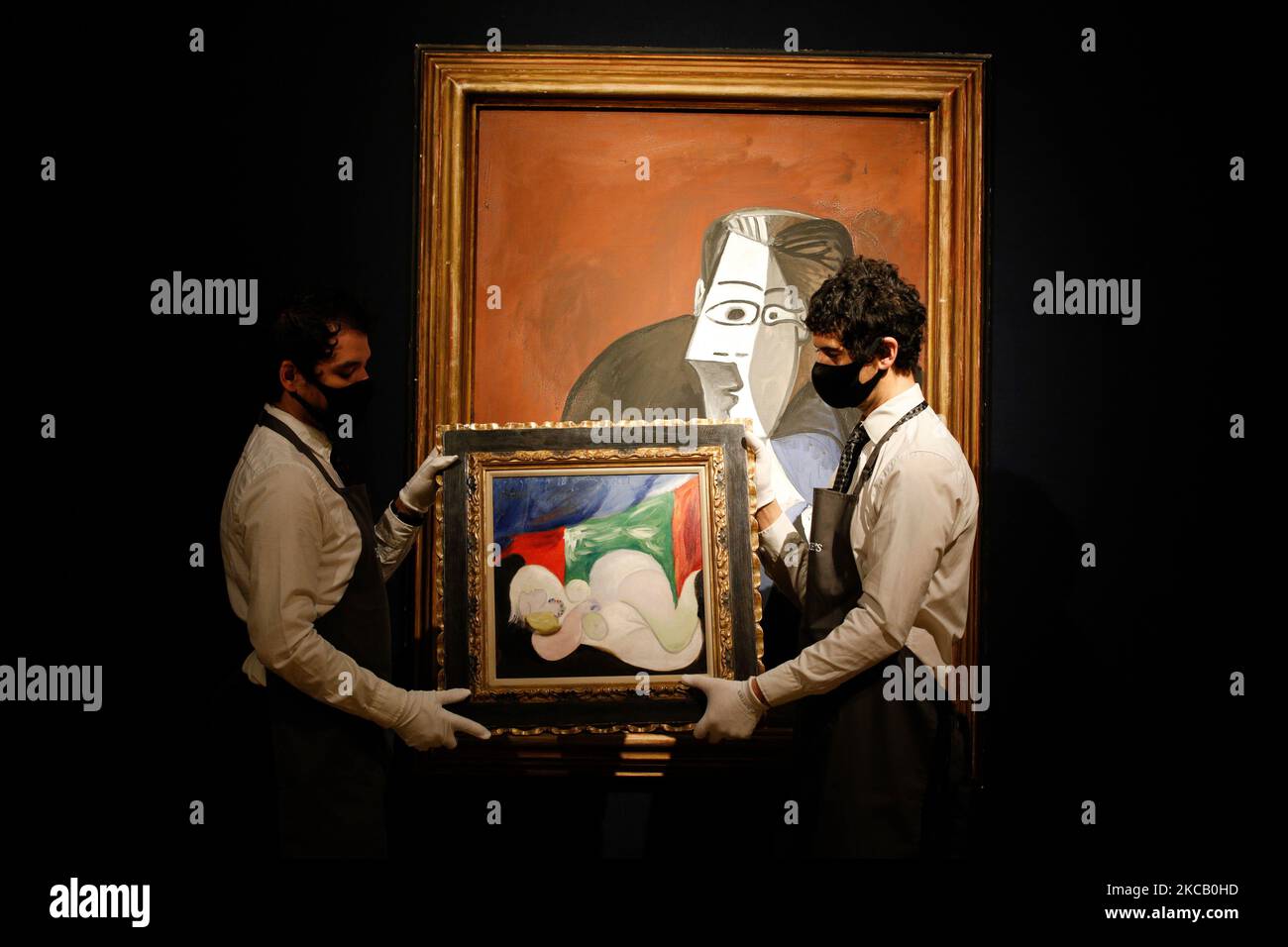 Members of staff pose holding oil on canvas work 'Femme nue couchee au collier (Marie-Thérèse)', by Pablo Picasso, estimated at GBP9,000,000-15,000,000, and in front of oil on canvas work 'Femme assise dans un fauteuil noir (Jacqueline)', also by Picasso, estimated at GBP6,000,000-9,000,000, during a press preview for the upcoming 20th Century Art and Art of the Surreal sale at Christie's auction house in London, England, on March 16, 2021. The sale takes place next Tuesday, March 23. (Photo by David Cliff/NurPhoto) Stock Photo
