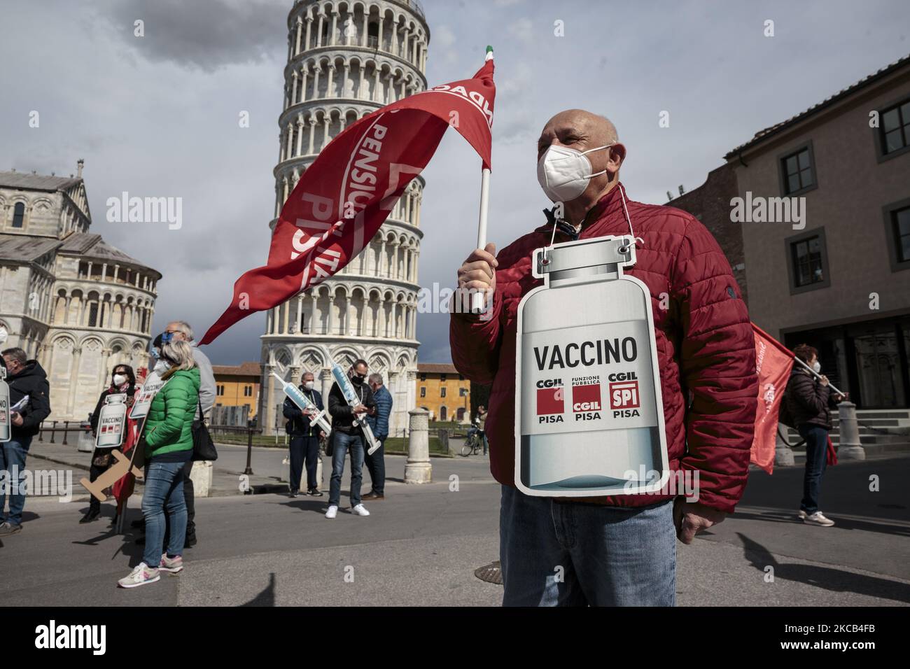 A retired man standing with a cardboard sign of the shape of a covid vaccine in front of the leaning tower in Pisa, Italy, on March 18, 2021. CGIL, The main trade union of Italy organized a Flash Mob in front of the leaning tower to ask for acceleration on the vaccination campaign against Covid-19, especially for the retired people who attended the event. (Photo by Enrico Mattia Del Punta/NurPhoto) Stock Photo