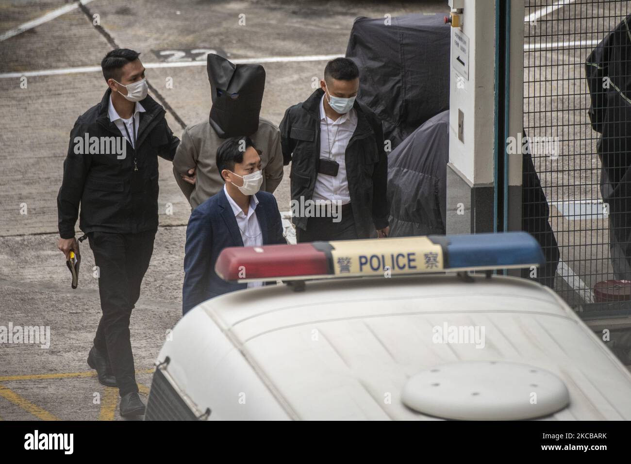 Police escort an unidentified man from a car to Tin Shui Wai Police Station who is one of the 12 Hong Kongers jailed by the mainland authorities for illegal border-crossing in Hong Kong, Monday, March 22, 2021. The activists completed their prison terms today after being sentenced to seven months following a dramatic attempt to flee Hong Kong by boat. (Photo by Vernon Yuen/NurPhoto) Stock Photo