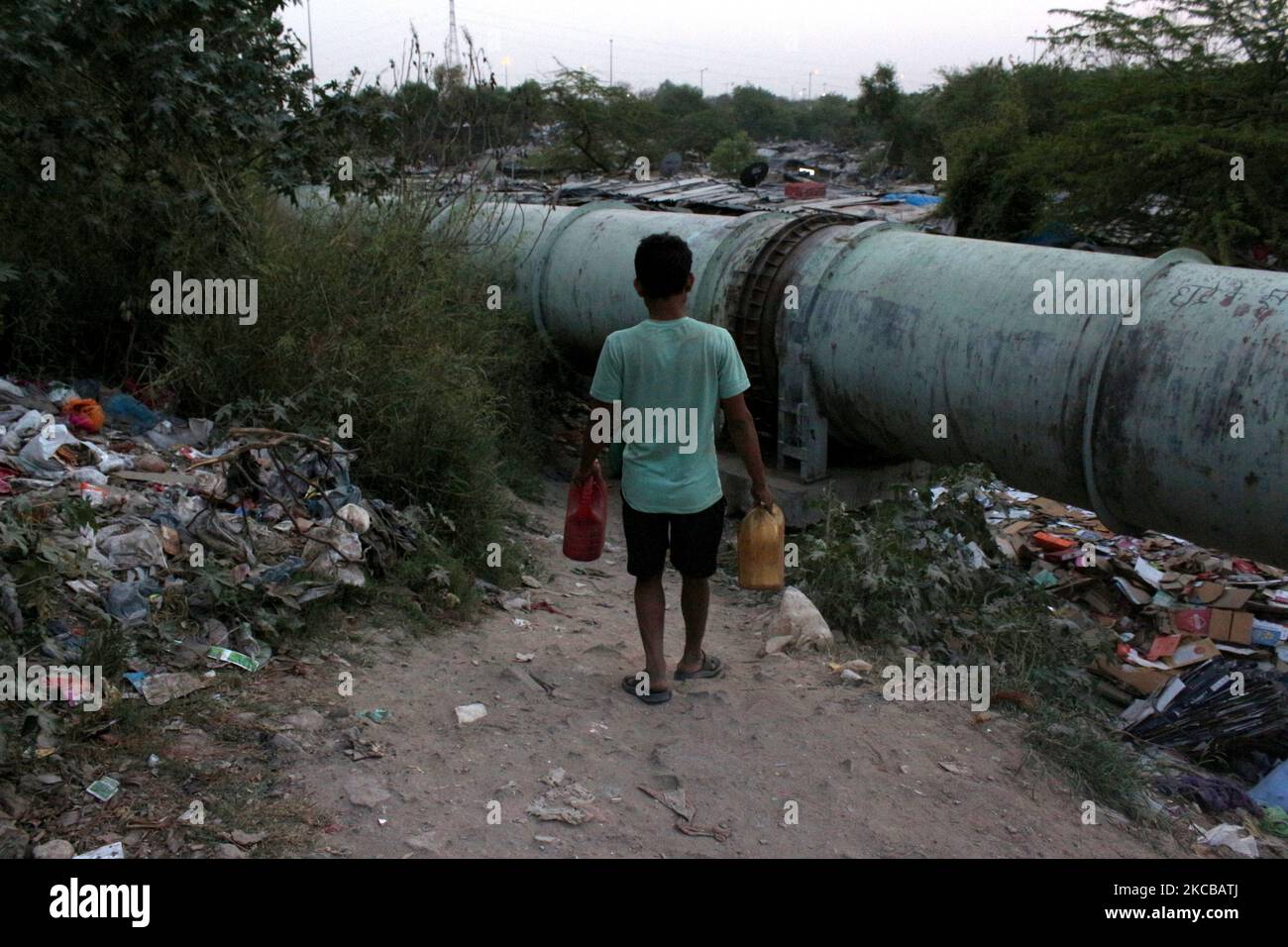 Container Slum A man arrives to fill plastic containers with water coming out of a ...