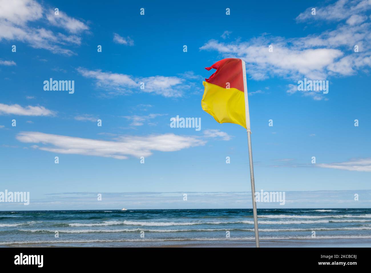 Red and Yellow Life Saving Flag on Gold Coast Beach Stock Photo