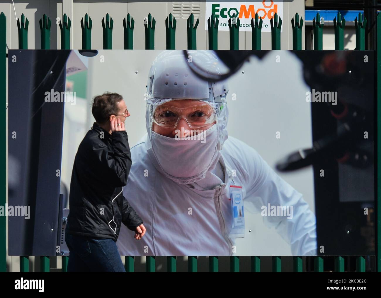 A man walks past a poster on the construction site fence of a new