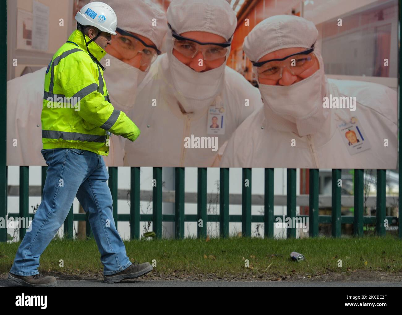 A man walks past the construction site fence of a new microchip