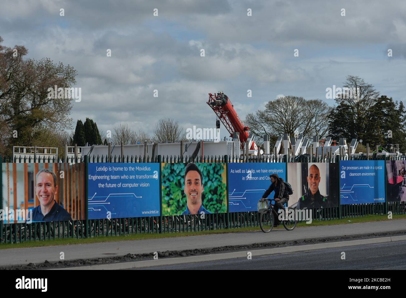 A man cycles by the construction site fence of a new microchip